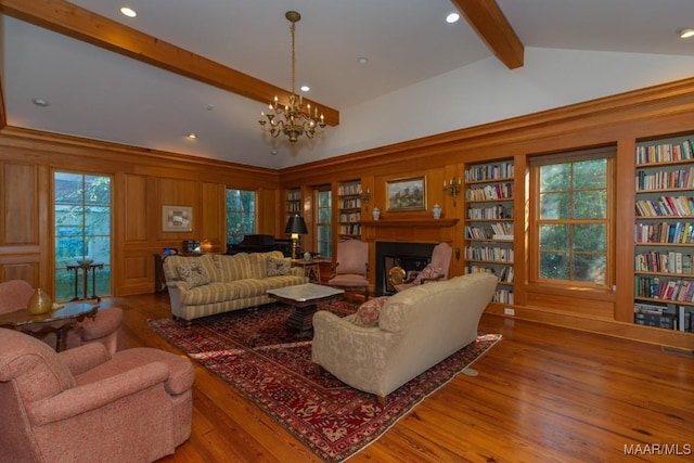 living room featuring hardwood / wood-style flooring, a notable chandelier, built in features, and vaulted ceiling with beams