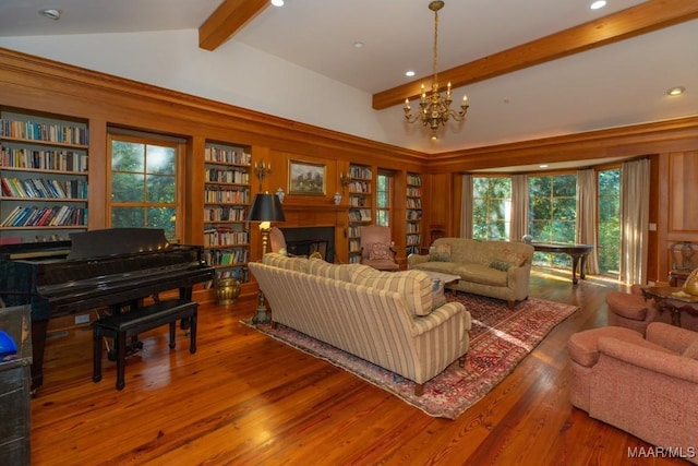 living room with a notable chandelier, built in shelves, wood-type flooring, and lofted ceiling with beams