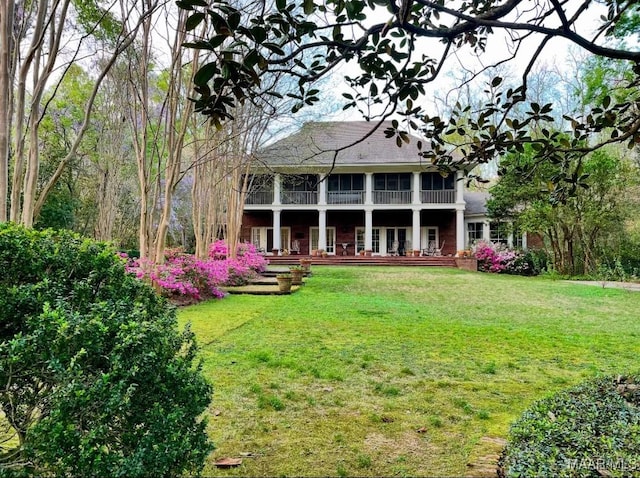 back of property with a sunroom and a lawn