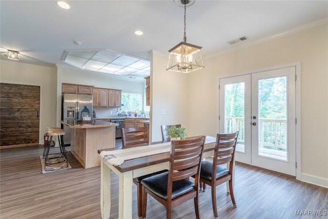 dining area featuring french doors, light wood-type flooring, a wealth of natural light, and ornamental molding