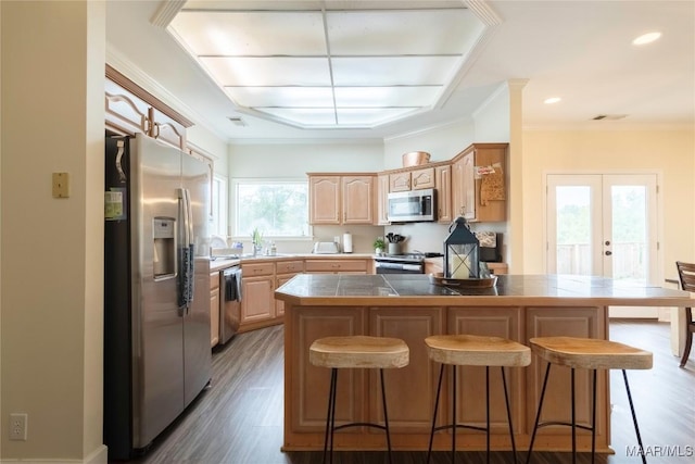 kitchen with appliances with stainless steel finishes, a center island, hardwood / wood-style flooring, and a healthy amount of sunlight