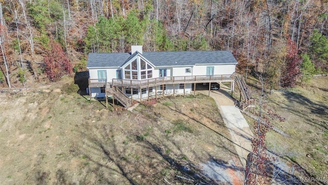 exterior space with stairs, a deck, a chimney, and a wooded view