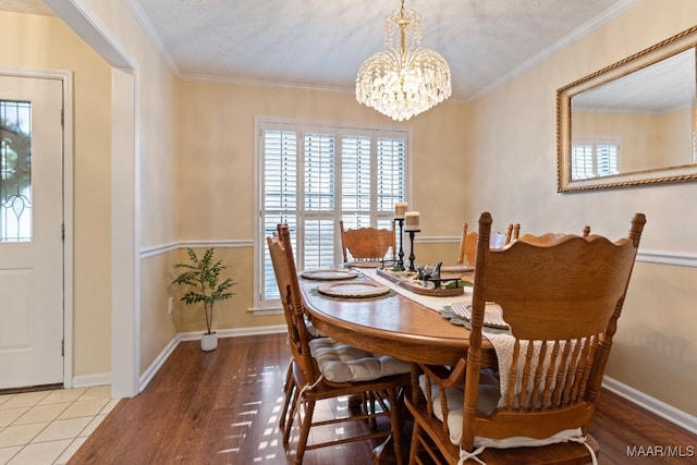 dining room featuring a textured ceiling, wood-type flooring, ornamental molding, and a chandelier