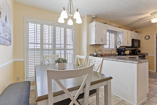 kitchen with pendant lighting, white cabinets, a textured ceiling, stainless steel range oven, and kitchen peninsula