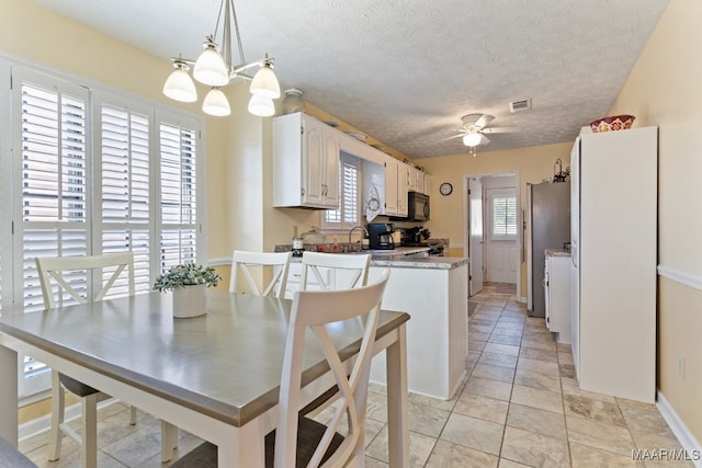 kitchen with black appliances, white cabinets, ceiling fan with notable chandelier, a textured ceiling, and decorative light fixtures