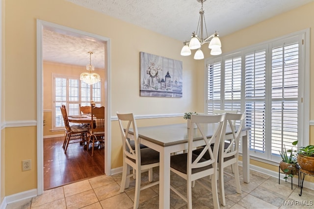 dining area with light hardwood / wood-style flooring, a textured ceiling, and a notable chandelier