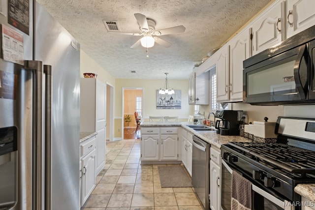 kitchen featuring white cabinetry, hanging light fixtures, stainless steel appliances, a textured ceiling, and ceiling fan with notable chandelier