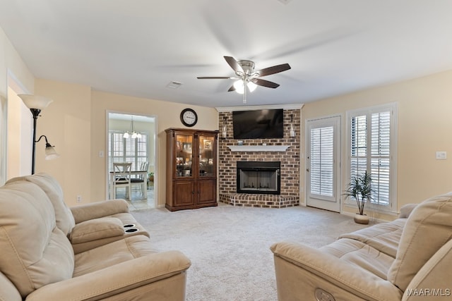 living room featuring a fireplace, light carpet, ceiling fan with notable chandelier, and a healthy amount of sunlight