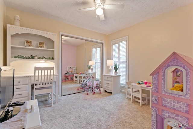 bedroom featuring a closet, a textured ceiling, light colored carpet, and ceiling fan