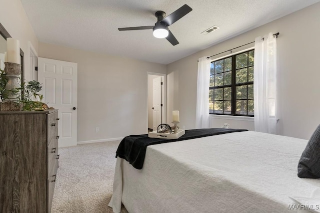 carpeted bedroom featuring ceiling fan and a textured ceiling