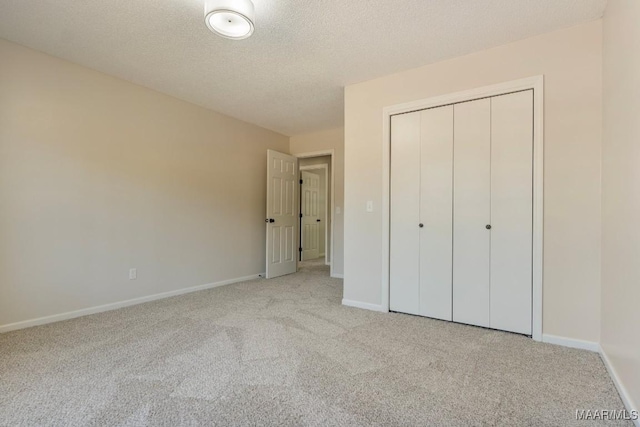 unfurnished bedroom with a textured ceiling, light carpet, and a closet