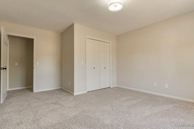 unfurnished bedroom featuring light carpet, a closet, and a textured ceiling