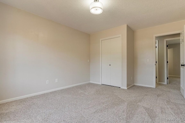 unfurnished bedroom featuring a textured ceiling, light colored carpet, and a closet