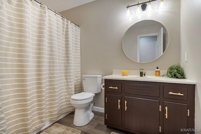 bathroom featuring vanity, wood-type flooring, a textured ceiling, and toilet