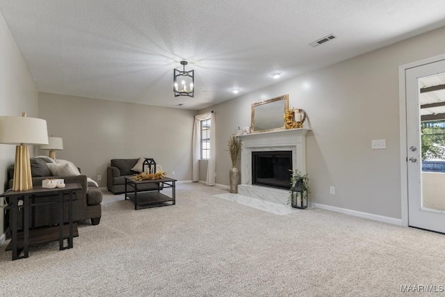 carpeted living room with a high end fireplace, a textured ceiling, and plenty of natural light