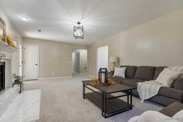 carpeted living room with a premium fireplace, a textured ceiling, and a chandelier