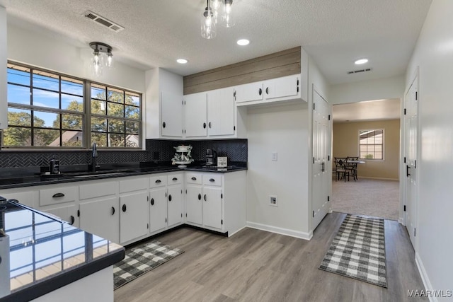 kitchen with white cabinets, light hardwood / wood-style floors, backsplash, and a textured ceiling