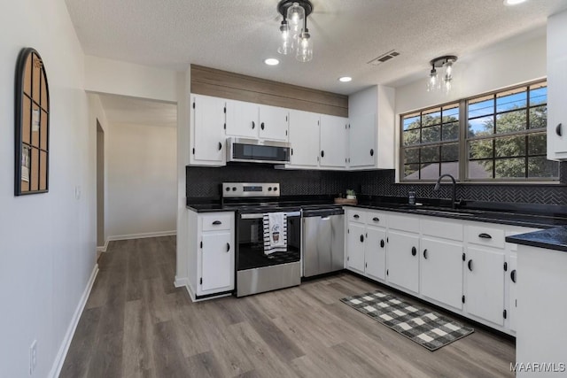 kitchen with sink, stainless steel appliances, light hardwood / wood-style flooring, a textured ceiling, and white cabinets