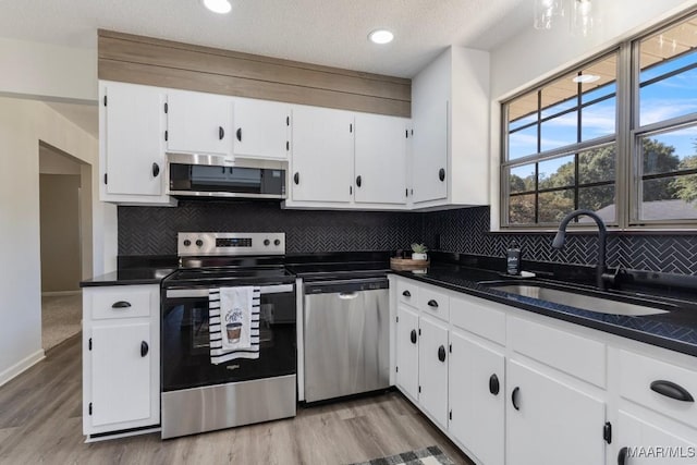 kitchen with decorative backsplash, a textured ceiling, stainless steel appliances, sink, and white cabinets