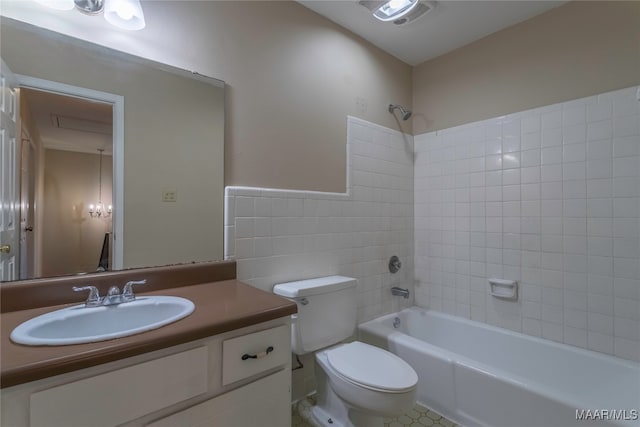 full bathroom featuring toilet, tile patterned floors, tile walls, vanity, and tiled shower / bath combo