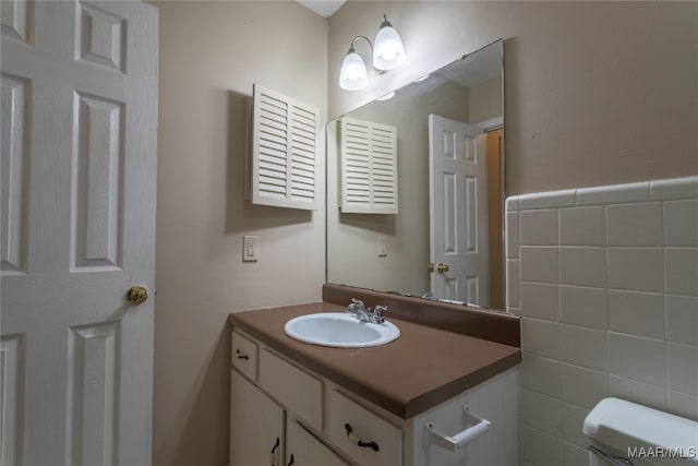 bathroom with toilet, vanity, and tile walls