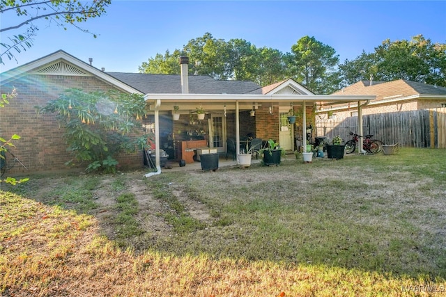 back of property featuring a patio area and a lawn