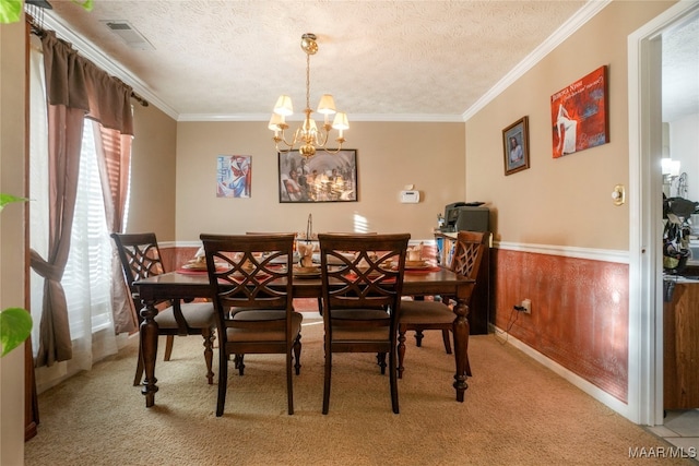 carpeted dining space with crown molding, wood walls, a textured ceiling, and a chandelier