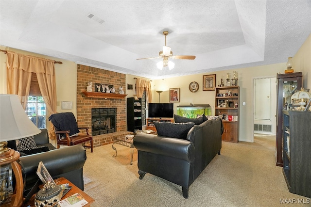 living room with a fireplace, a raised ceiling, a textured ceiling, ceiling fan, and light carpet