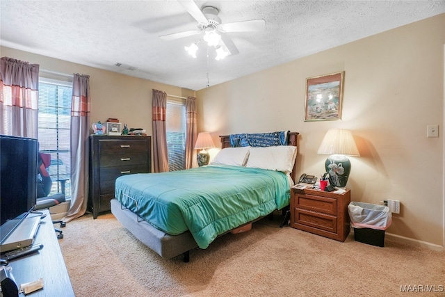 bedroom featuring a textured ceiling, light colored carpet, and ceiling fan