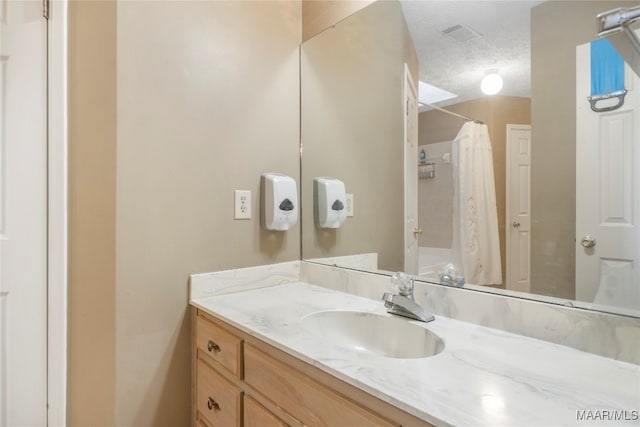 bathroom featuring vanity, a textured ceiling, and walk in shower