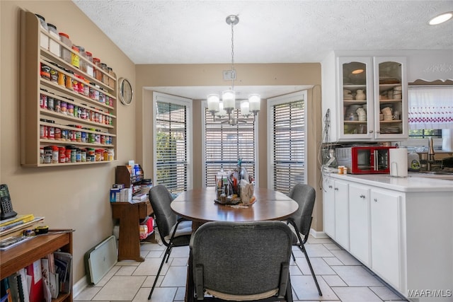 tiled dining room featuring a notable chandelier, a textured ceiling, and sink