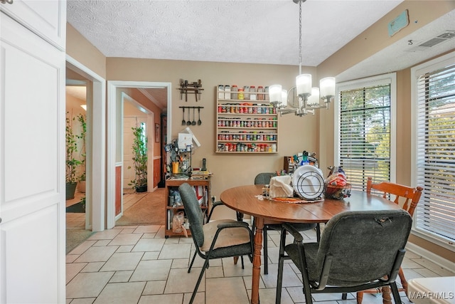 dining room featuring a chandelier, a textured ceiling, and light tile patterned floors