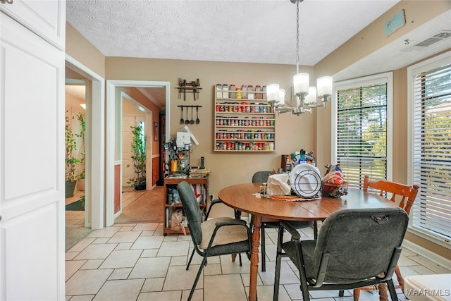 tiled dining room with an inviting chandelier and a textured ceiling