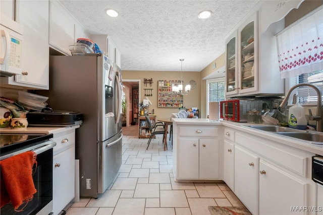 kitchen with white appliances, sink, hanging light fixtures, white cabinetry, and an inviting chandelier