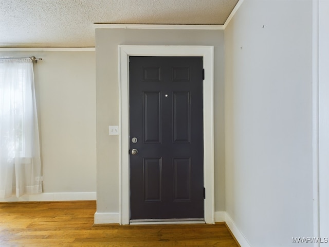 foyer entrance featuring a textured ceiling, ornamental molding, and hardwood / wood-style floors