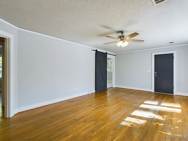 spare room featuring ornamental molding, a textured ceiling, a barn door, and wood-type flooring