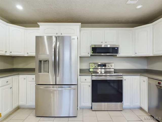 kitchen featuring a textured ceiling, white cabinetry, stainless steel appliances, and light tile patterned floors