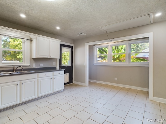 kitchen with white cabinetry, light tile patterned floors, a textured ceiling, and sink