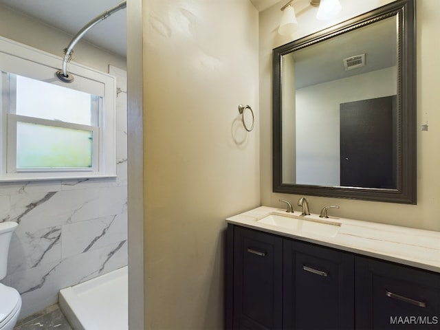 bathroom featuring toilet, walk in shower, vanity, and tile walls