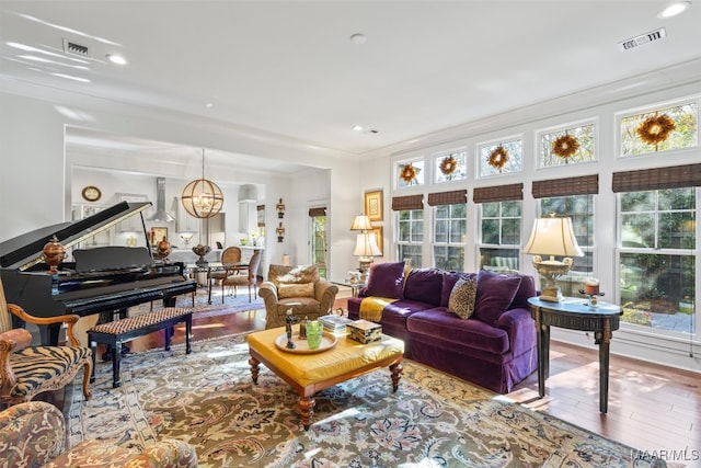 living room with an inviting chandelier, hardwood / wood-style floors, and crown molding