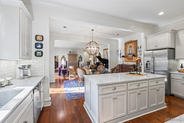 kitchen featuring tasteful backsplash, hanging light fixtures, white cabinetry, stainless steel appliances, and dark wood-type flooring