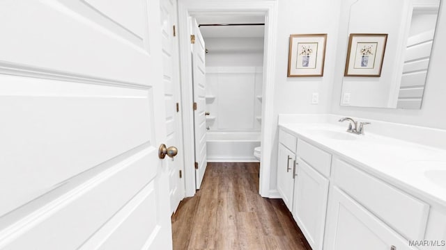 full bathroom with hardwood / wood-style floors, vanity, toilet, and  shower combination