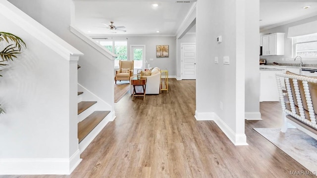 interior space featuring ceiling fan, light hardwood / wood-style floors, and crown molding