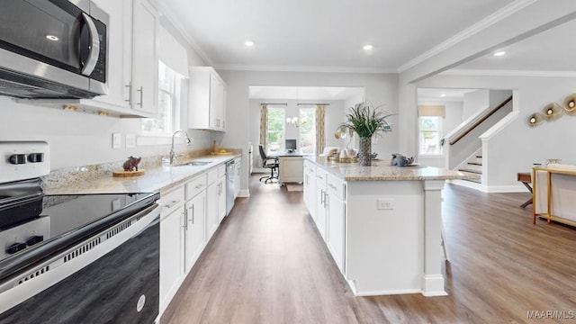 kitchen with white cabinetry, sink, stainless steel appliances, light hardwood / wood-style flooring, and a kitchen island