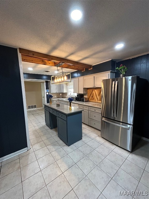 kitchen featuring a textured ceiling, white cabinetry, decorative light fixtures, beam ceiling, and stainless steel refrigerator