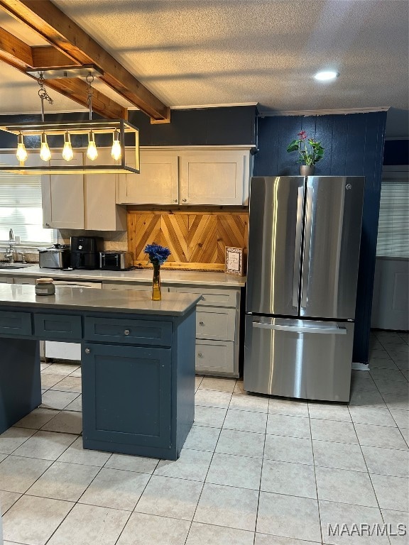 kitchen with sink, stainless steel fridge, beamed ceiling, decorative light fixtures, and light tile patterned floors