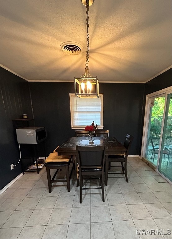 tiled dining space featuring an inviting chandelier, crown molding, a textured ceiling, and wooden walls