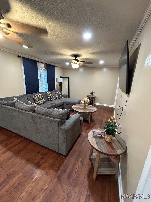 living room featuring ornamental molding, dark wood-type flooring, a textured ceiling, and ceiling fan