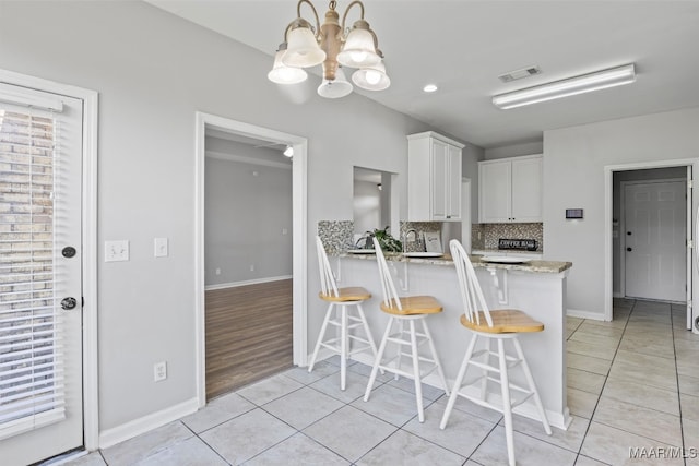 kitchen featuring kitchen peninsula, white cabinets, a breakfast bar area, light wood-type flooring, and sink