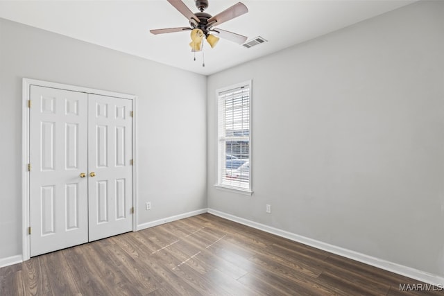 unfurnished bedroom featuring dark wood-type flooring, a closet, and ceiling fan